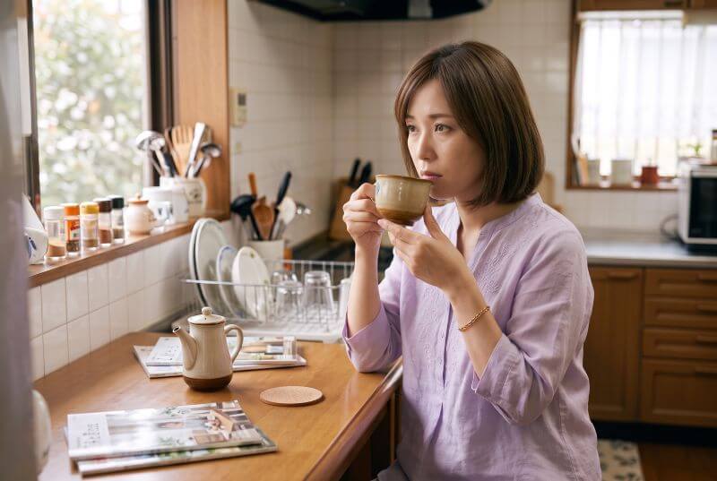 台所でコーヒーを飲みながら、ひと息ついている女性